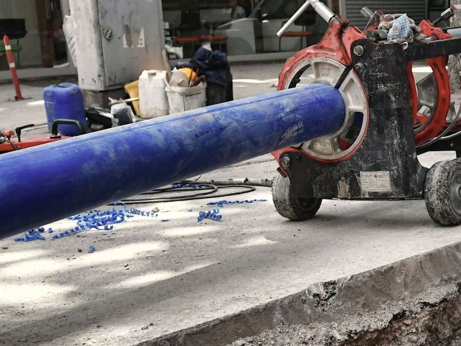 Țeavă albastră de polietilenă pentru apă, prinsă în mașina de sudură cap la cap, lângă șanț