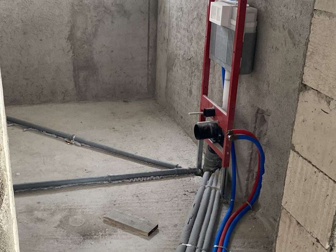 Cadru roșu pentru vas WC suspendat montat pe un perete de beton, cu țevile de alimentare