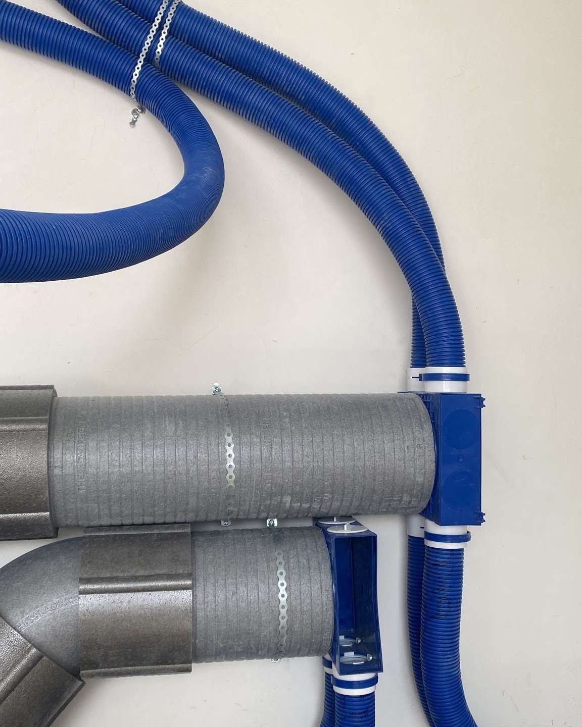 Tuburi flexibile albastre de ventilație și conducte izolate gri racordate la distribuitoare